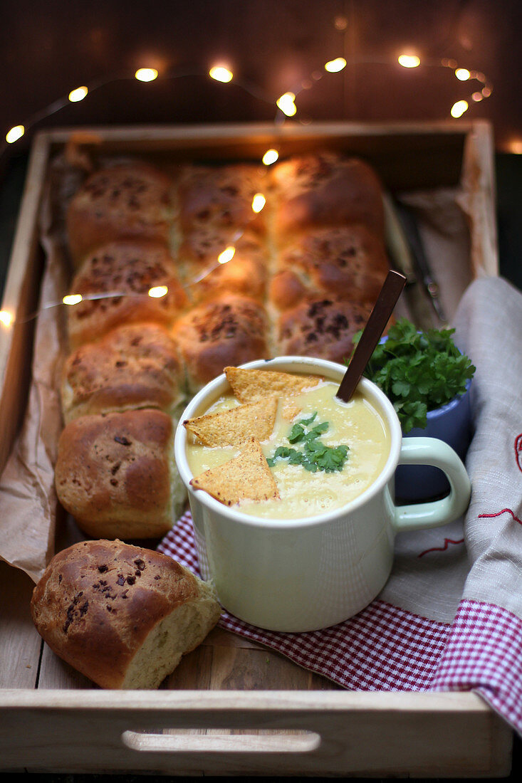 Mais-Curry-Suppe serviert in Tasse mit Tortillachips und Hefegebäck