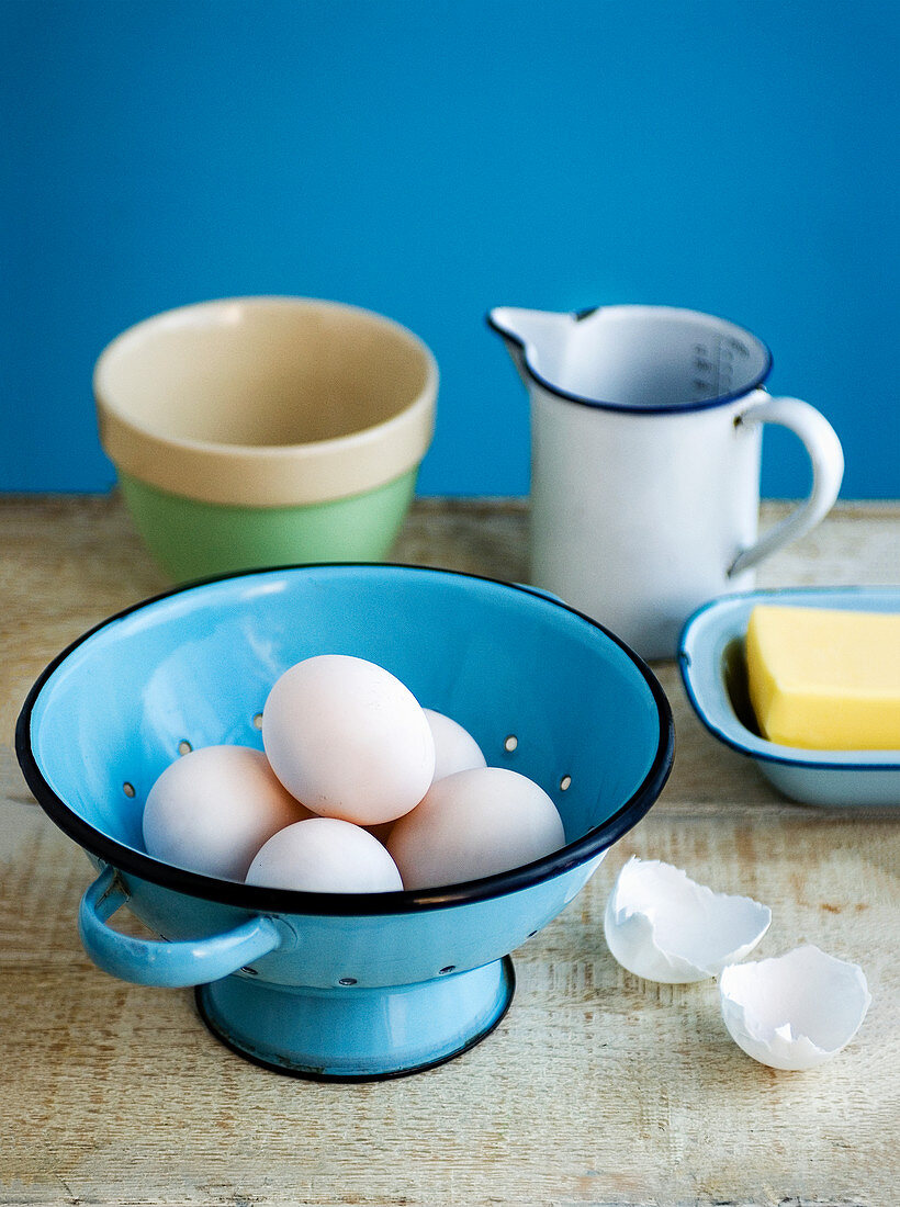 weiße Eier in blauem Emailleseiher dahinter Butter und Emaille-Meßbecher