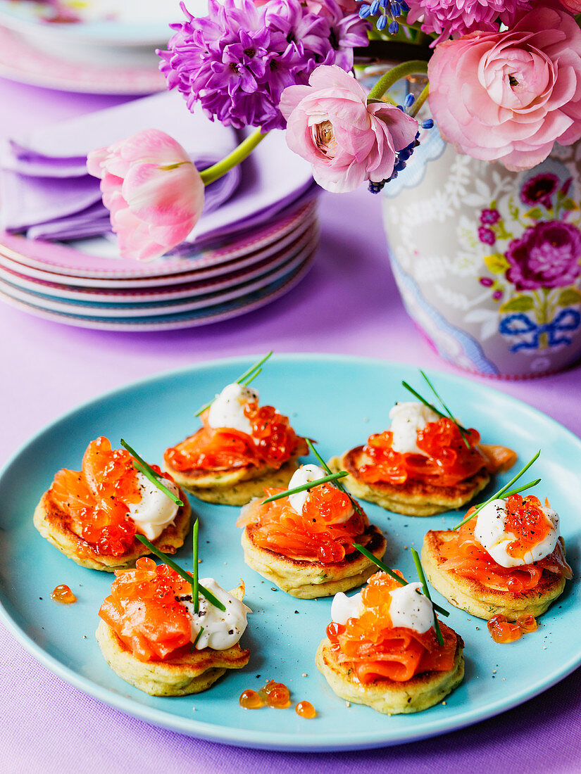 Easter lunch of smoked salmon and salmon caviar on blinis o an Easter table setting