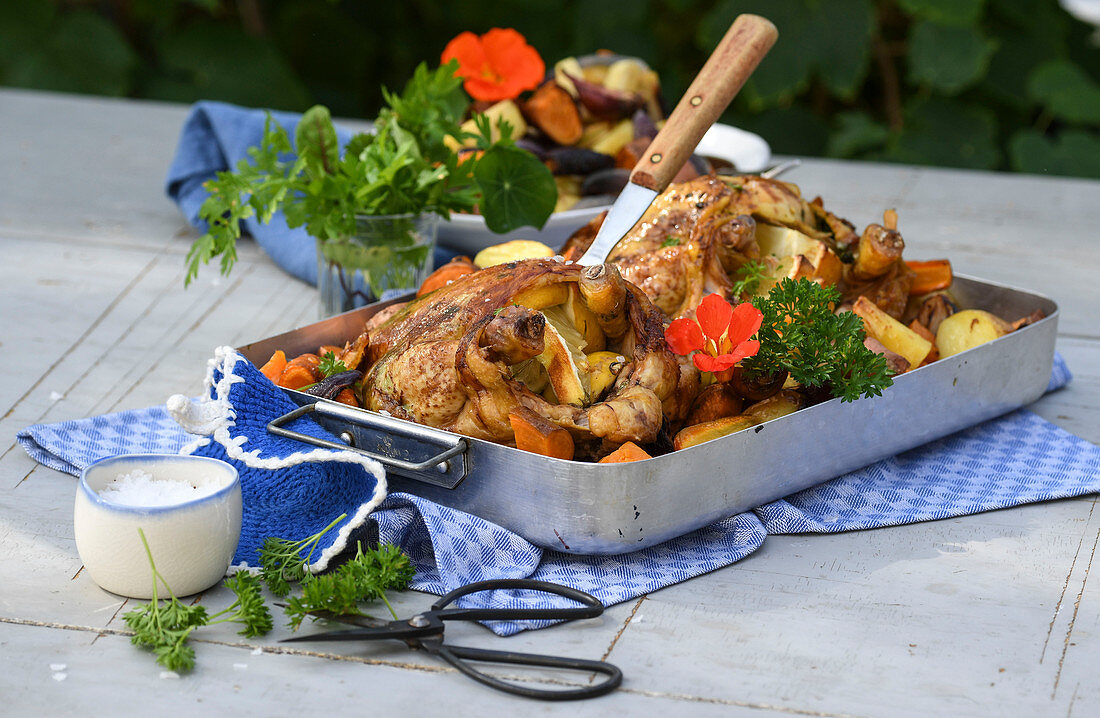 Gegrilltes Ofenhähnchen mit Wurzelgemüse auf Tisch im Freien