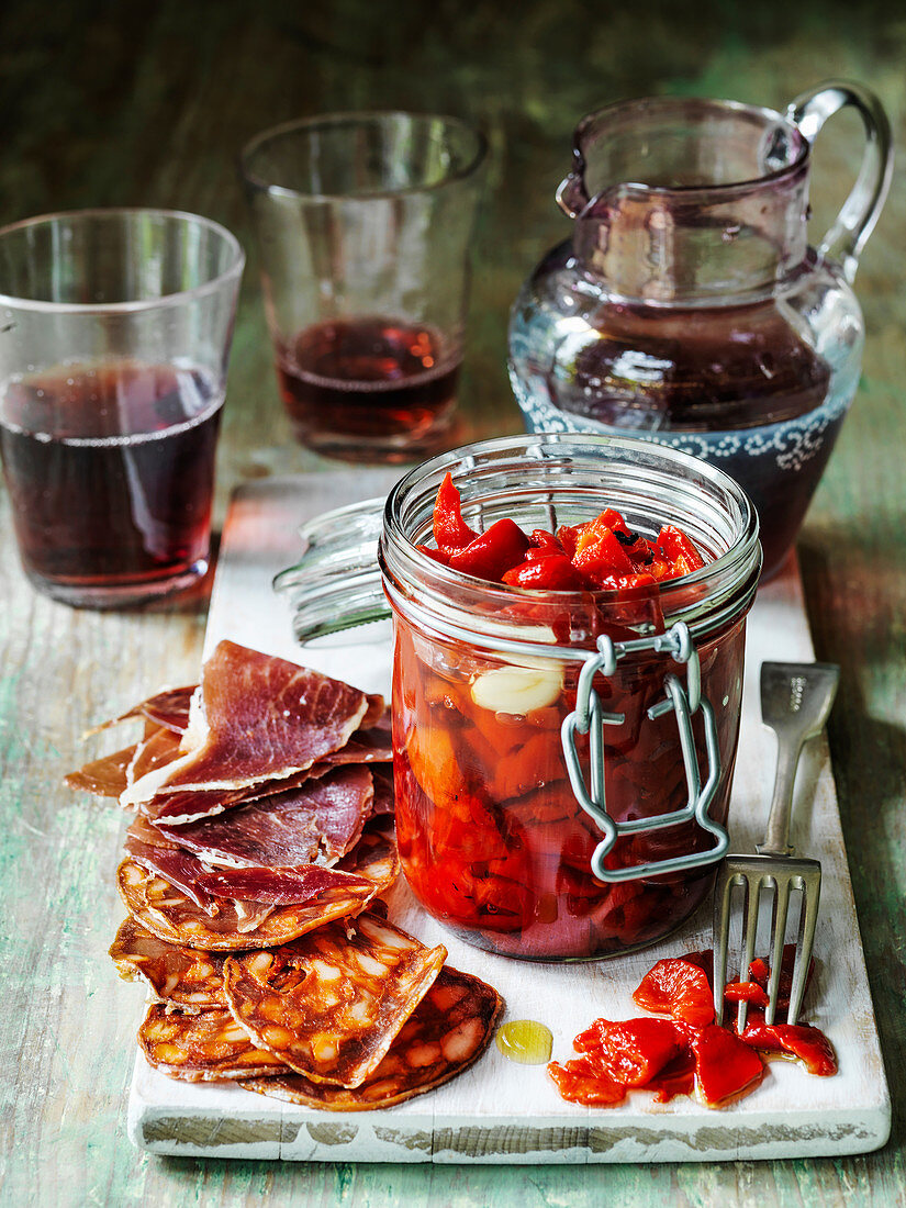 Spanish roast peppers in oil and garlic in jar with chorizo iberico ham and sangria