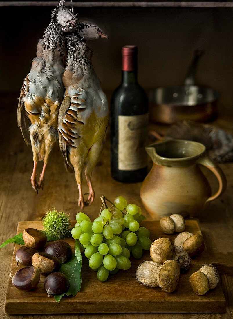 Still life of partridge chestnuts grapes and porcini mushrooms