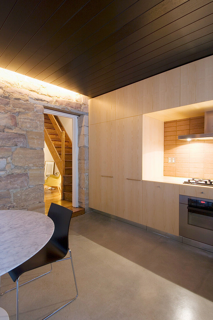 Modern fitted kitchen in pale wood with dark wooden ceiling