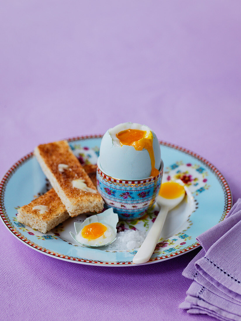 Weichgekochtes Frühstücksei im Eierbecher mit gebutterten Toaststreifen