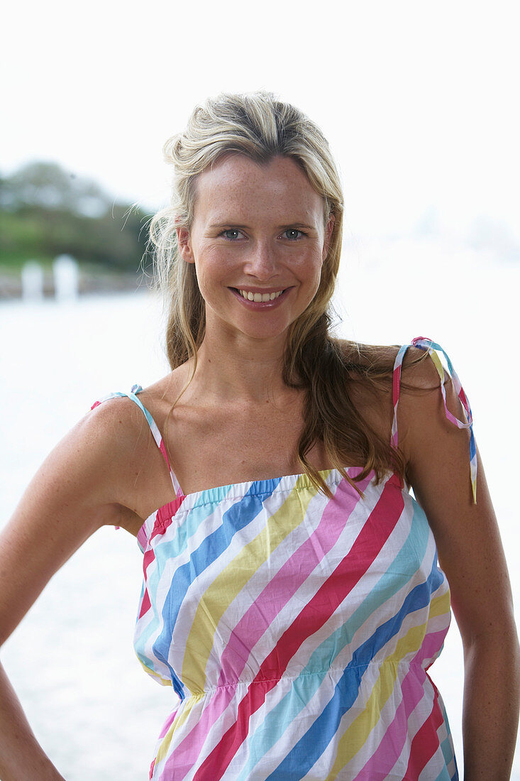 A young blonde woman on a beach wearing a light-blue top