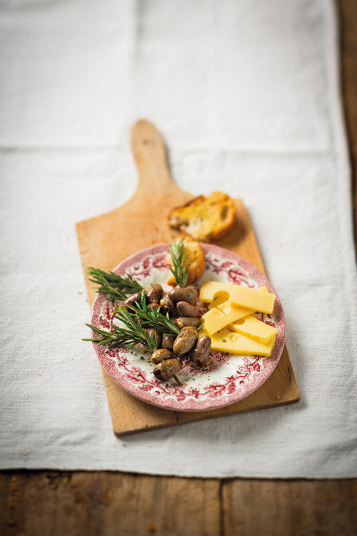 Rosmarin-Hühnerherzspieße serviert mit Käse und Röstbrot