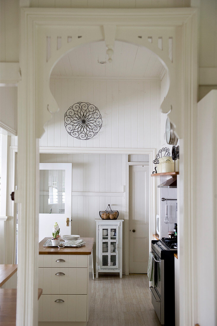 View through arched doorway into white country-house kitchen