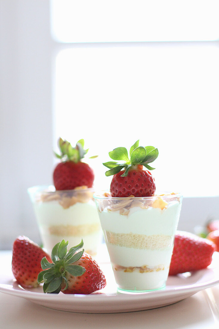A layered dessert with strawberries and flaked almonds in glasses
