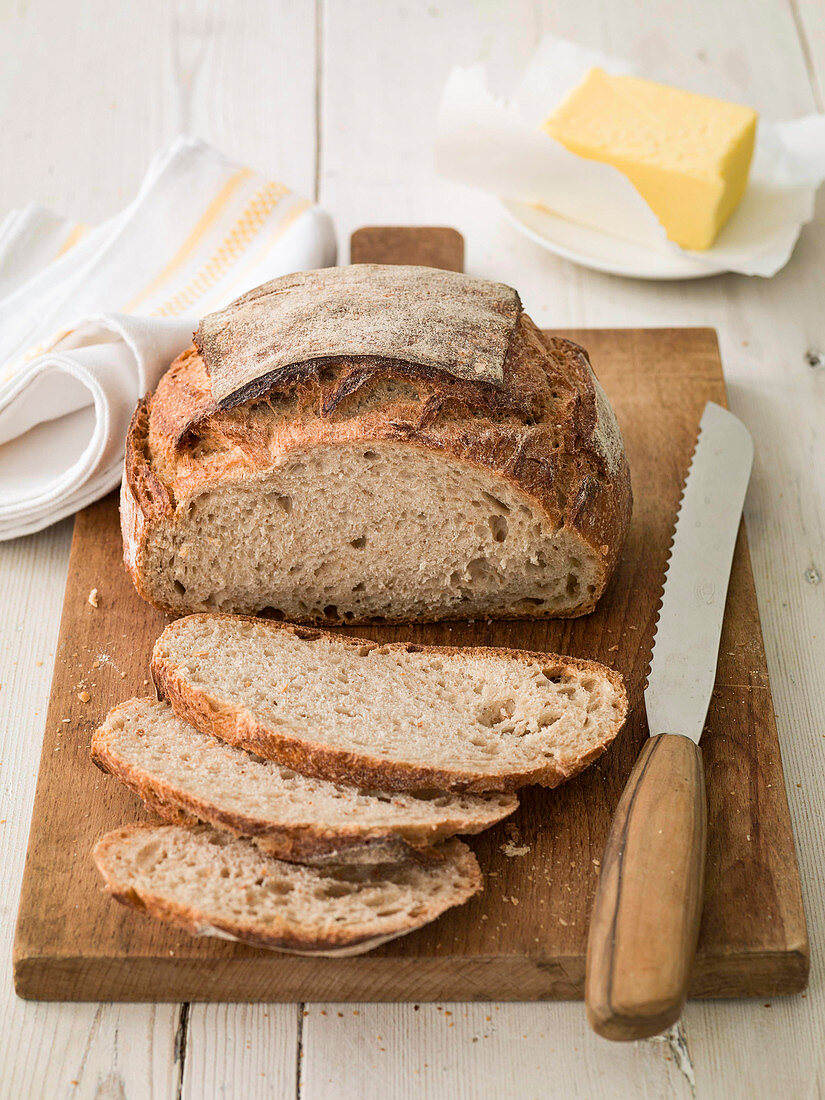 Rustic French loaf sliced with butter and bread knife