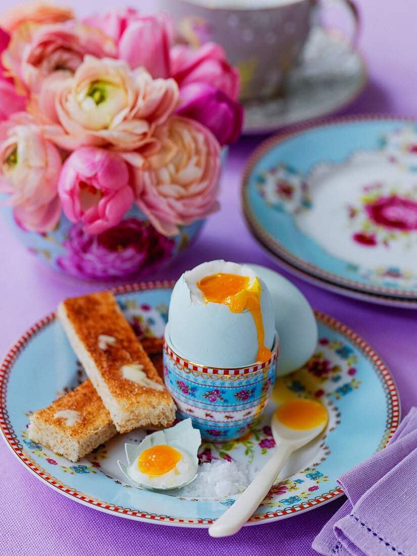 Egg And Soldiers (weich gekochtes Ei mit Toaststicks, England) und üppiger Blumenstrauß