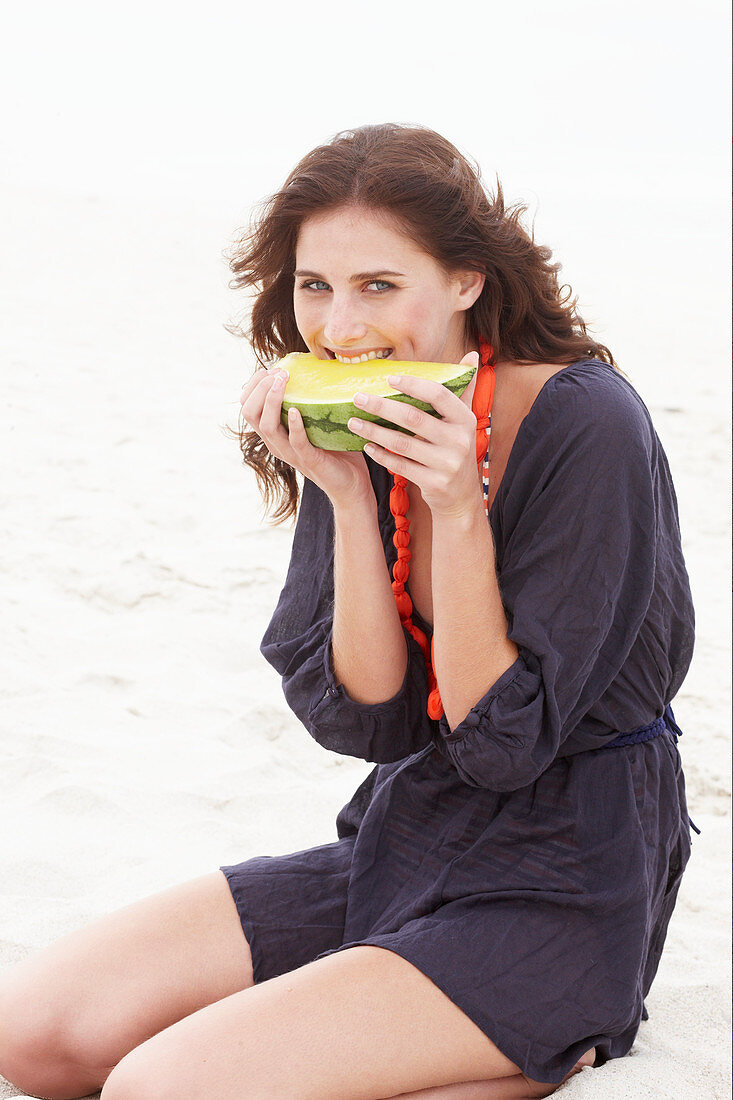 Brünette Frau im lila Strandkleid mit Melone