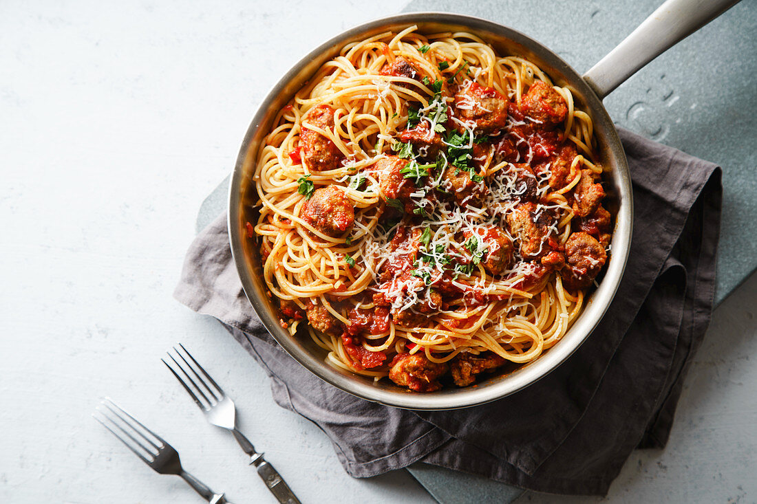 Spaghetti mit Fleischbällchen, Tomatensauce, Petersilie und Käse