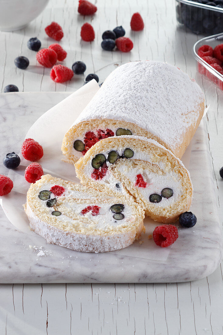 Sponge roll with cream and raspberries and blueberries