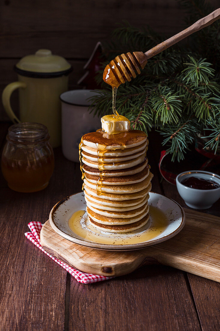 Stack of tasty pancakes served with butter and honey