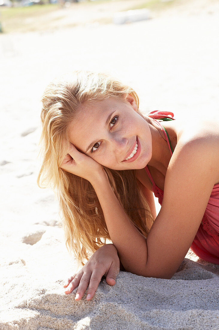 Junge blonde Frau im rosa Top am Strand