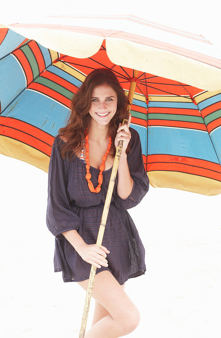 A brunette woman wearing a purple bath robe with a colourful parasol