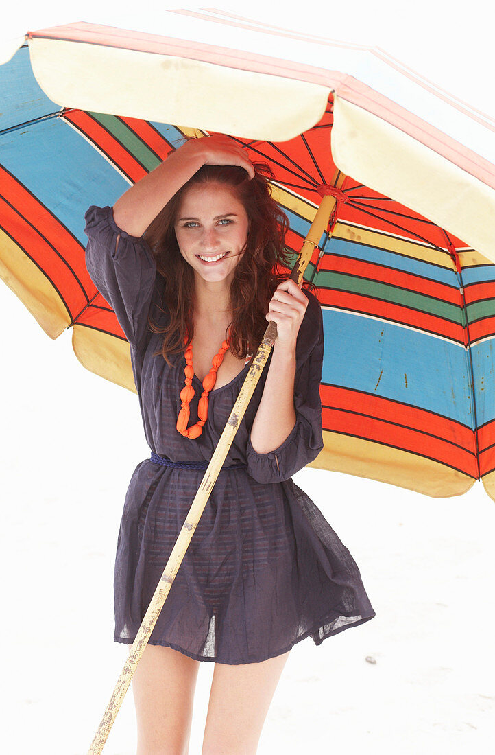 A brunette woman wearing a purple bath robe with a colourful parasol