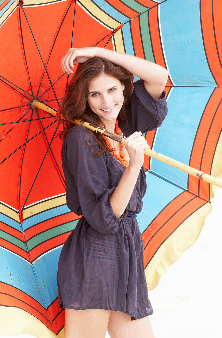 A brunette woman wearing a purple bath robe with a colourful parasol