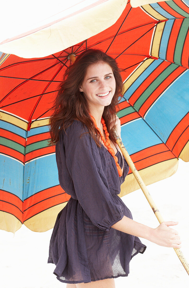 A brunette woman wearing a purple bath robe with a colourful parasol