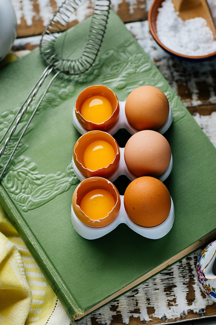 Stand with whole and cracked eggs on green book