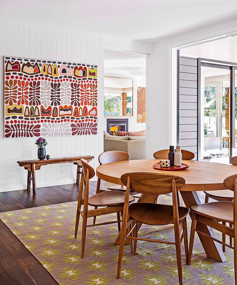 Wooden chairs around round dining table on carpet with ethnic pattern