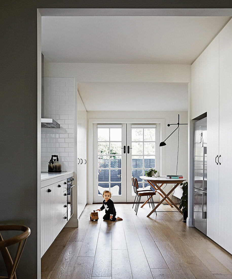 Child plays on the floor of a kitchen with a dining area
