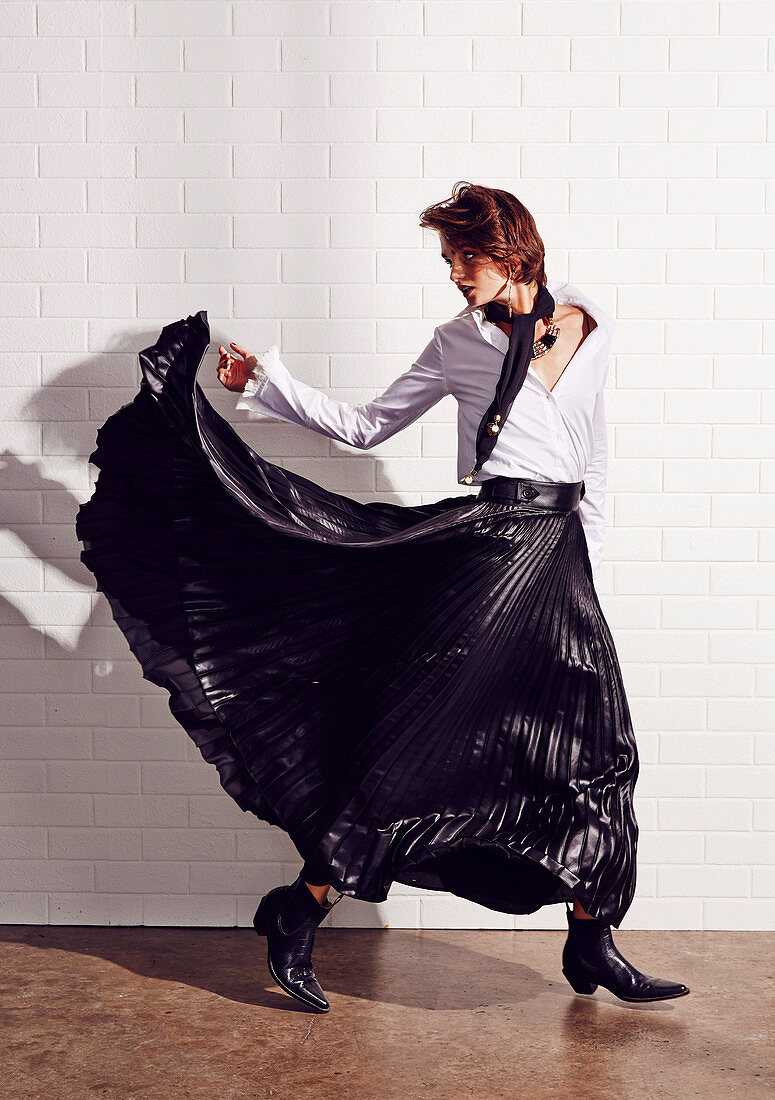 A young woman wearing a white shirt and a black pleated skirt