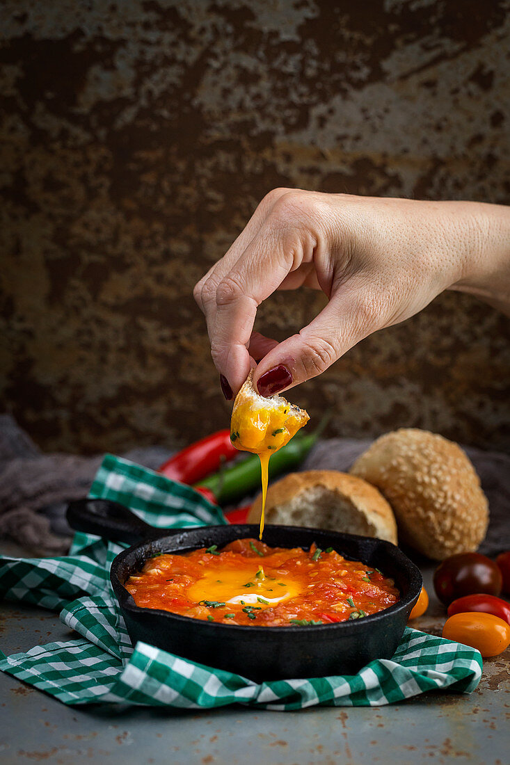 Spiegeleier mit Tomaten und Paprika in der Pfanne serviert mit Brot zum Dippen (Spanien)