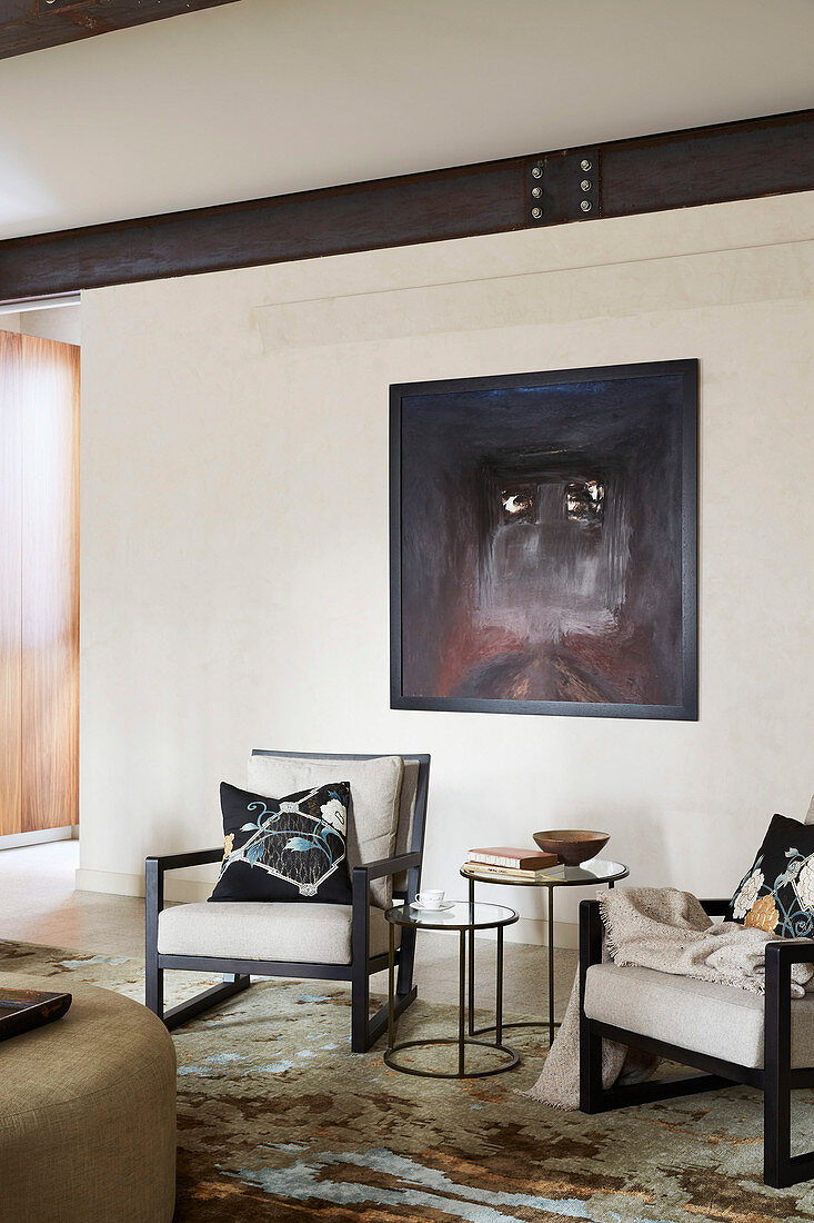 Two upholstered chairs under black paintings in the living room