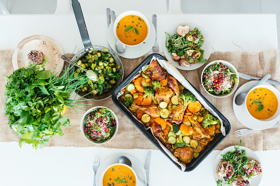 Lunch table filled with autumn dinner - pumpkin soup, roasted chicken and salad