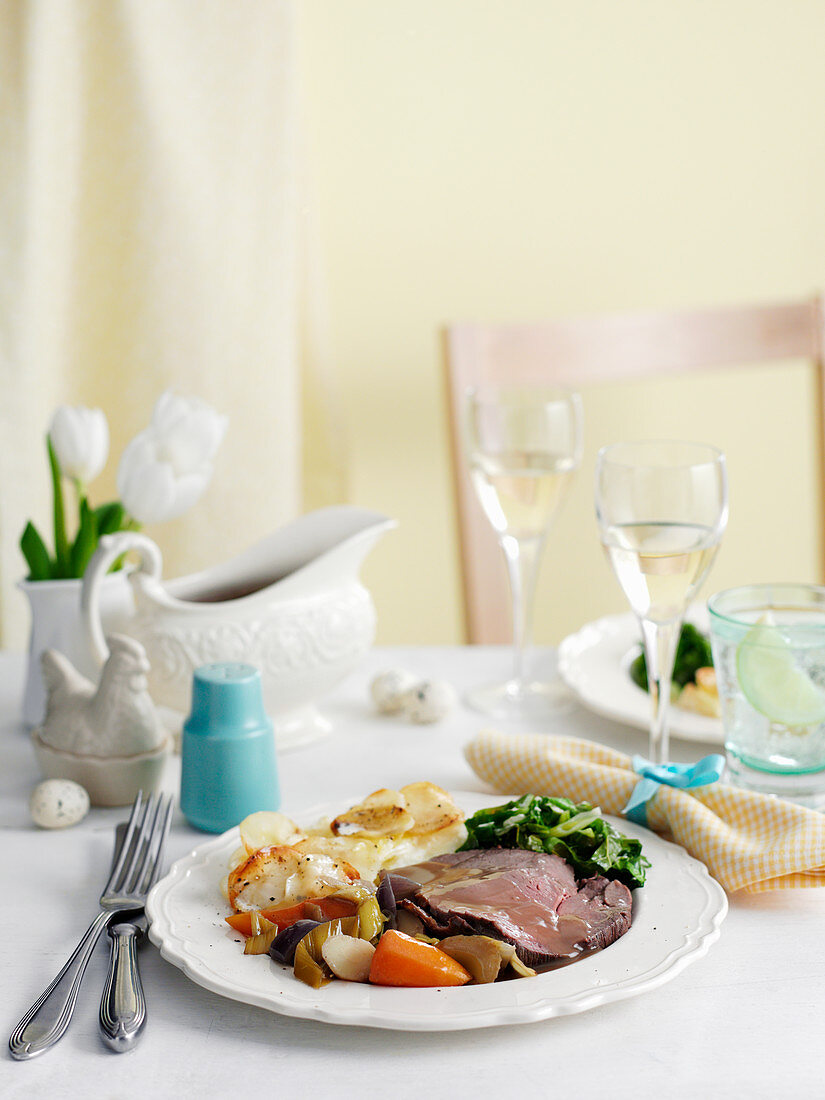 Rinderbraten in Scheiben mit Gratin Dauphinoise auf österlichem Tisch