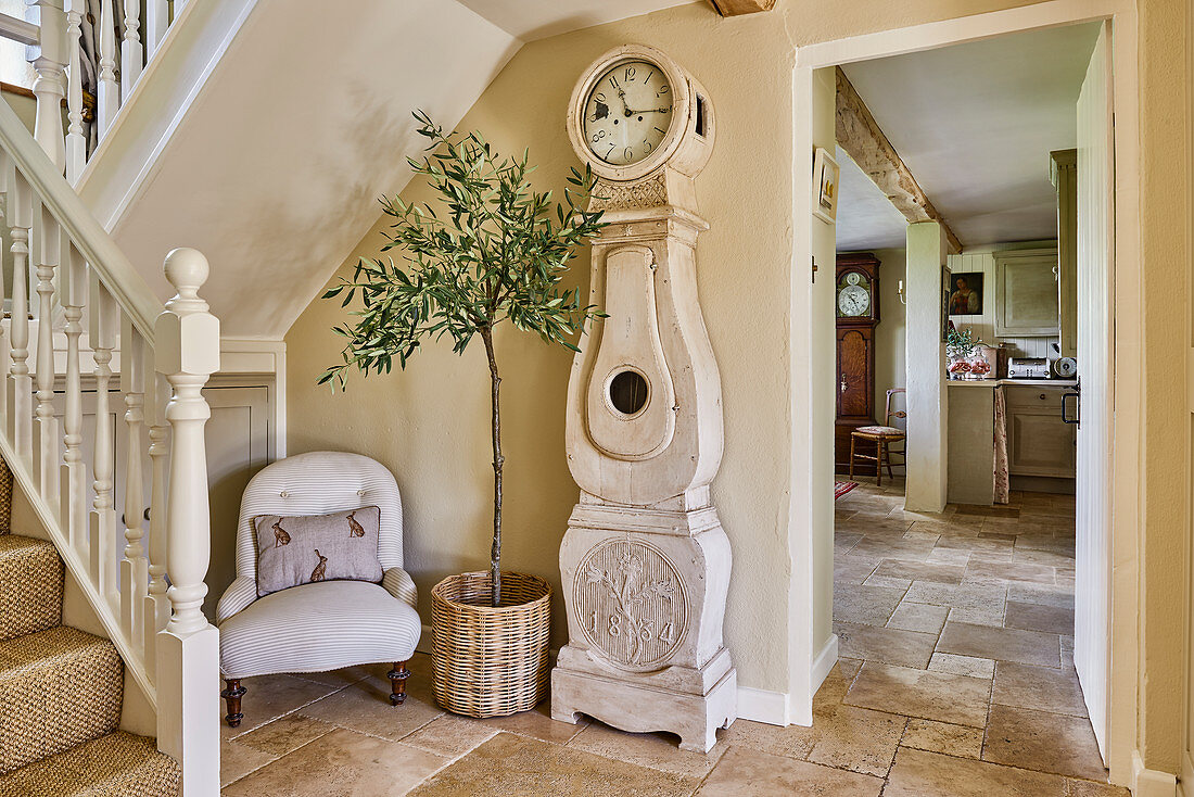 Antik Standuhr, Olivenbäumchen und Sessel im Treppenhaus