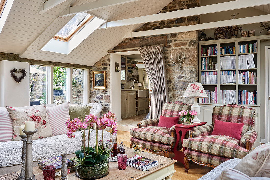 Tartan armchairs, bookcase and stone wall in attic living room