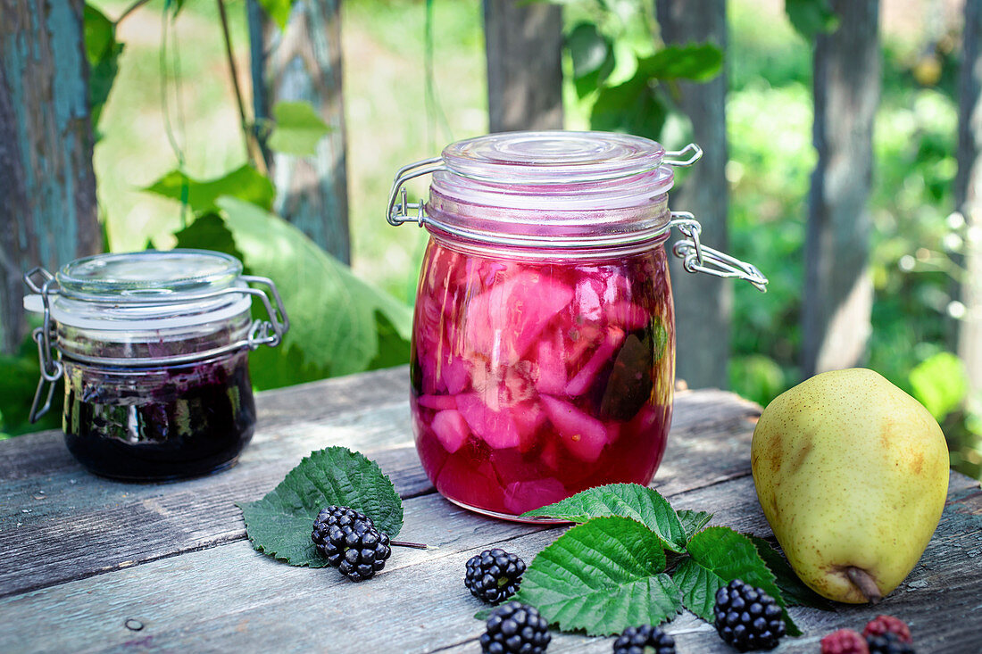 Birnenkompott und Brombeermarmelade in Gläsern auf Gartentisch