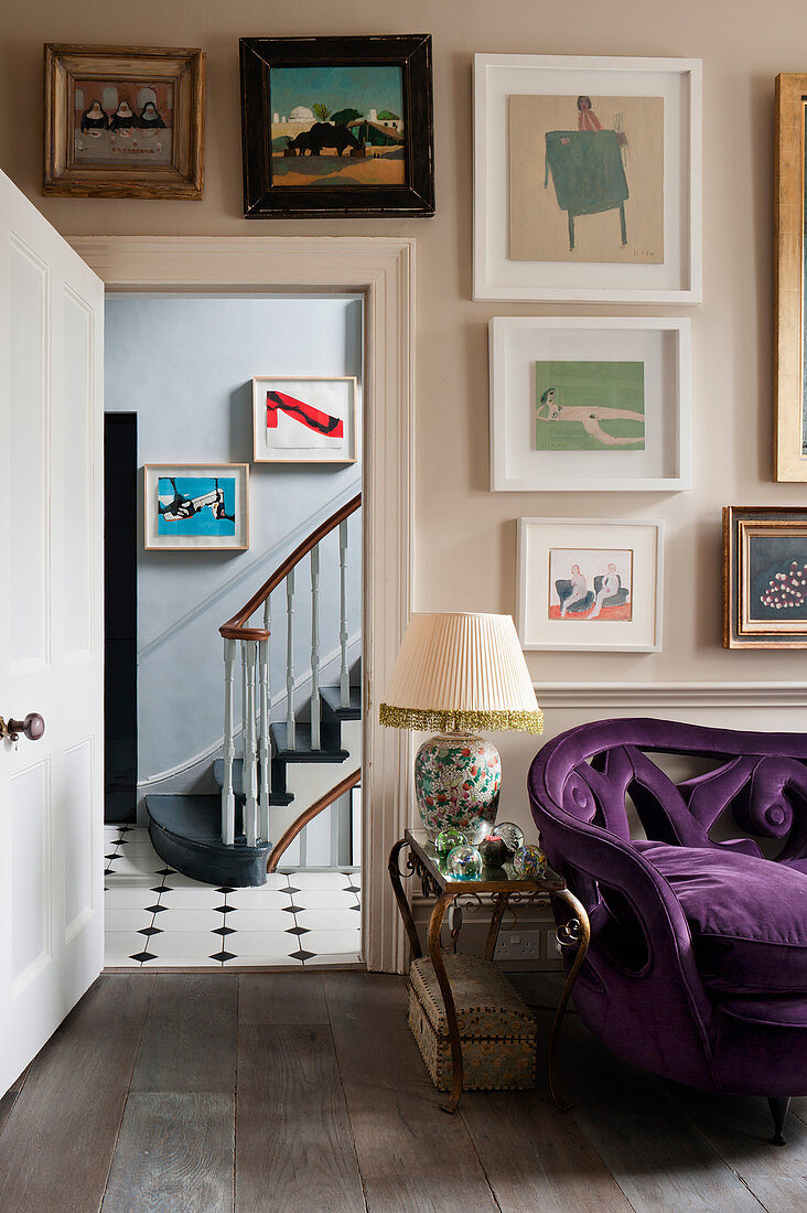 A purple sofa upholstered in velvet in living room with assorted artworks