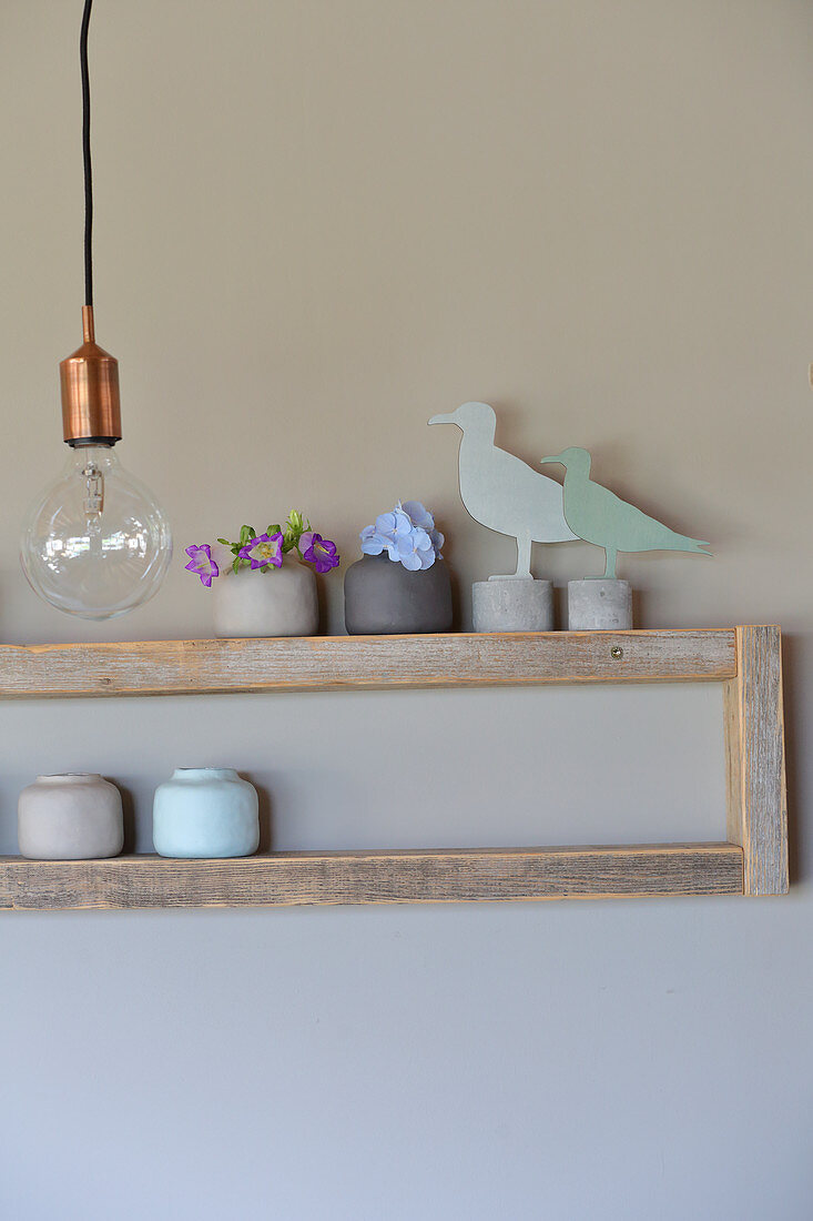 Bird ornaments and miniature ceramic vases on simple wooden shelves
