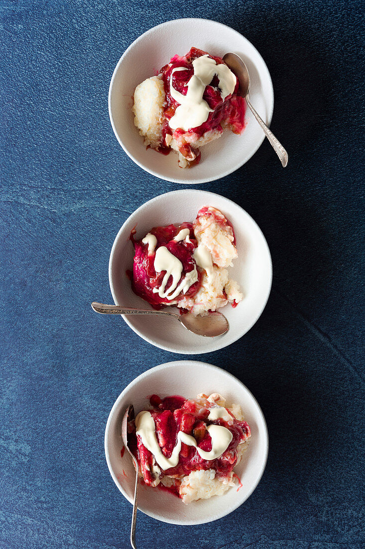 Three bowls of rice pudding with rhubarb and cream