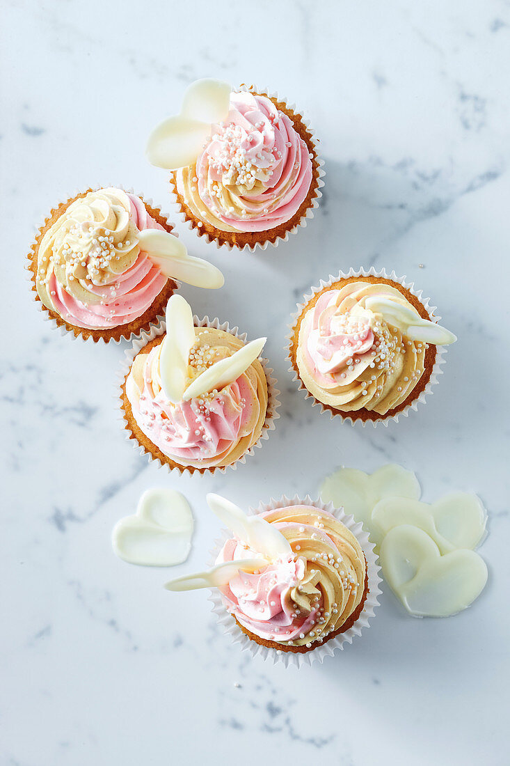 Kokos-Cupcakes mit zweifarbiger Buttercreme und weissen Schokoladenherzen