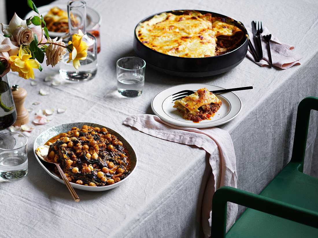 Gedeckter Tisch mit Lasagne und andalusischem Spinat mit Kichererbsen