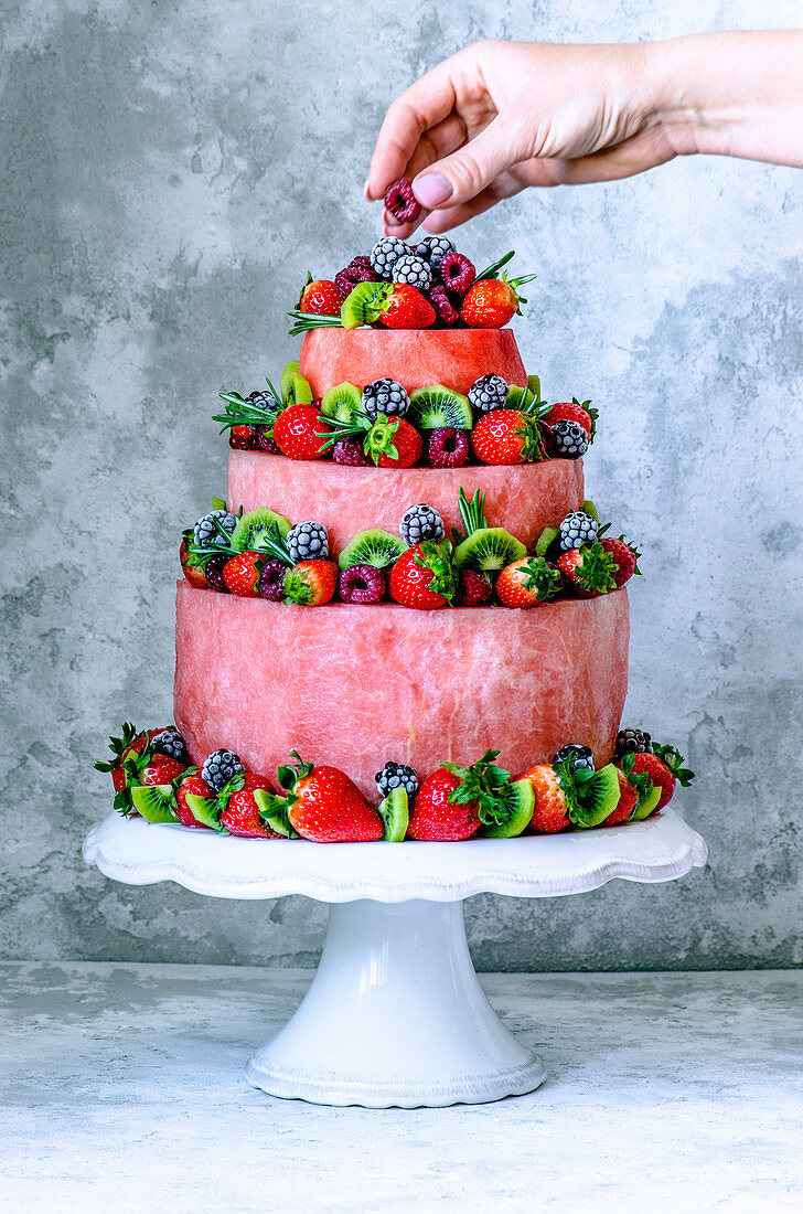 Dreistöckige Torte mit Wassermelone, Erdbeeren, Himbeeren, Kiwi, Brombeeren und Rosmarin