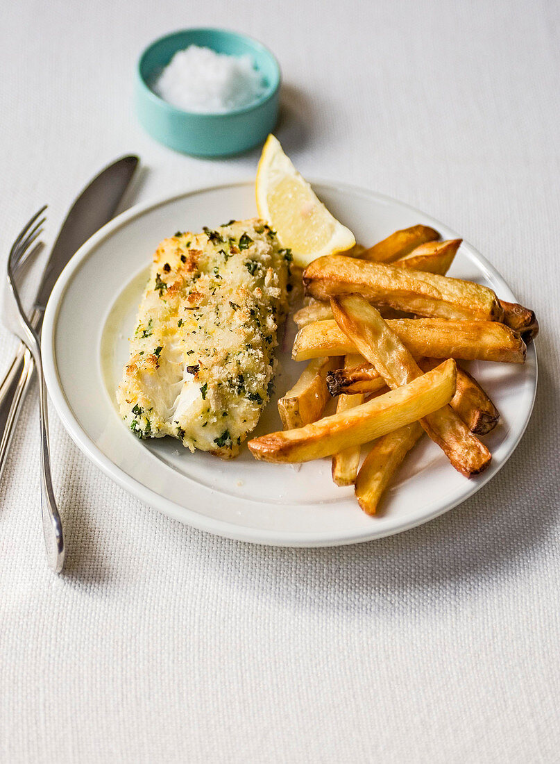 Fish and chips with herb breaded cod and sea salt in blue dish