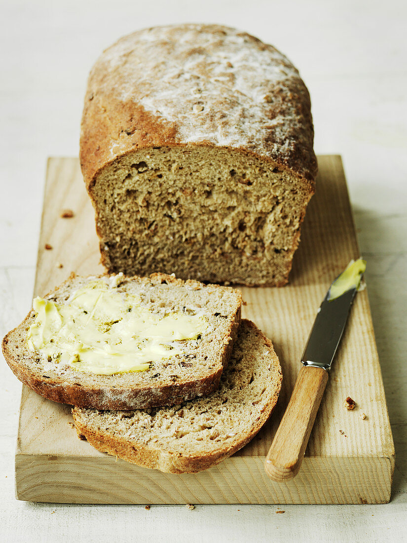 Organic brown bread country loaf with buttered slices