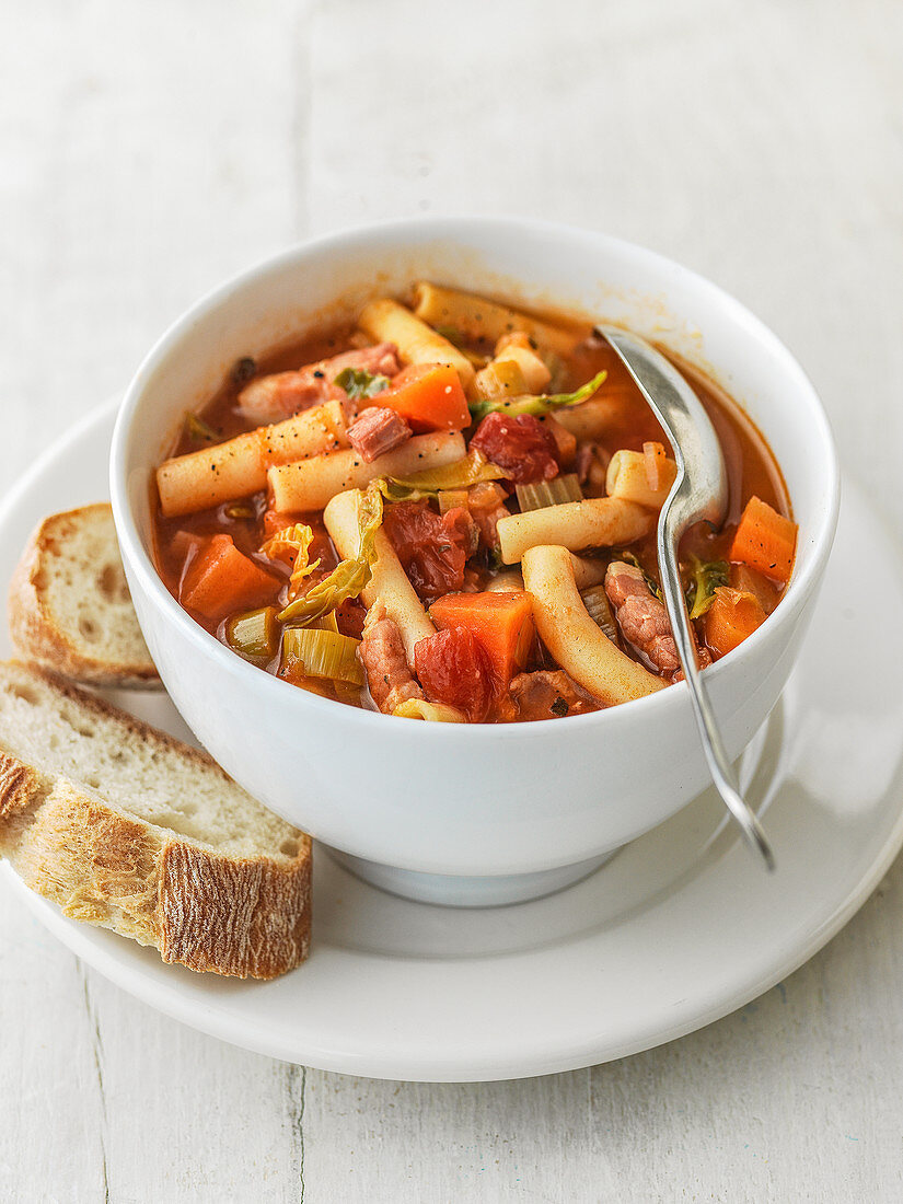 Minestrone soup in bowl with celery, tomatoes, green cabbage pancetta leeks and maccaroni