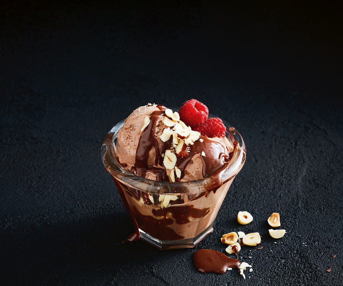 A cup of chocolate and nut ice cream with raspberries