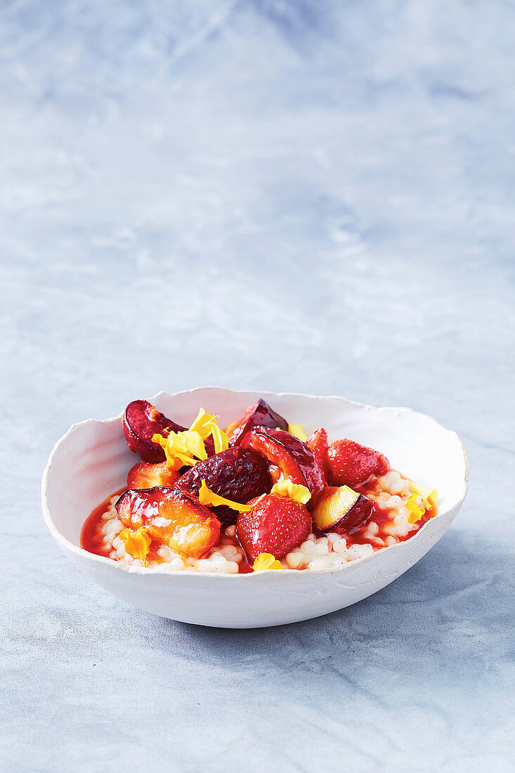 Pearl couscous pudding with coconut milk, strawberries and plums