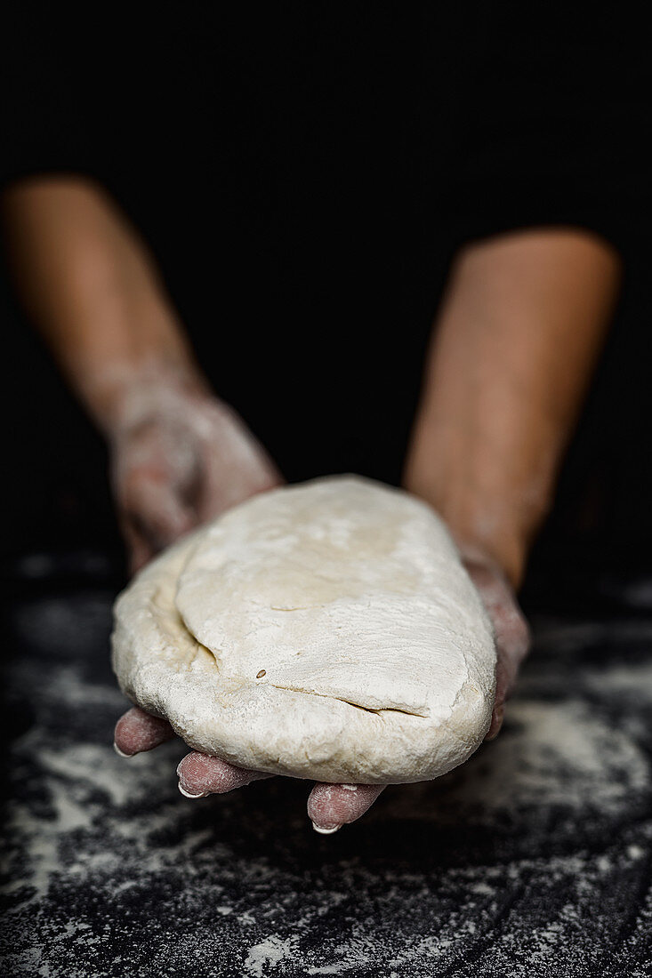 Woman's hands kneading bread on kitchen table