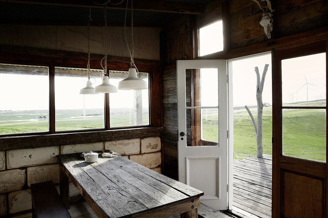 Wooden table with bench in rustic hut with limestone wall