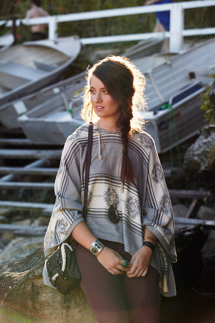 A young woman wearing a Western-style outfit consisting of trousers, a poncho and a bag