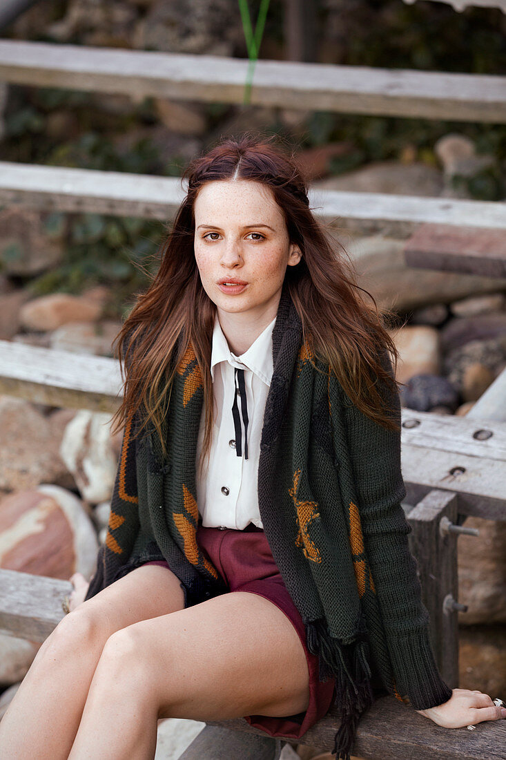 A young brunette woman wearing a jacket, a blouse and shorts