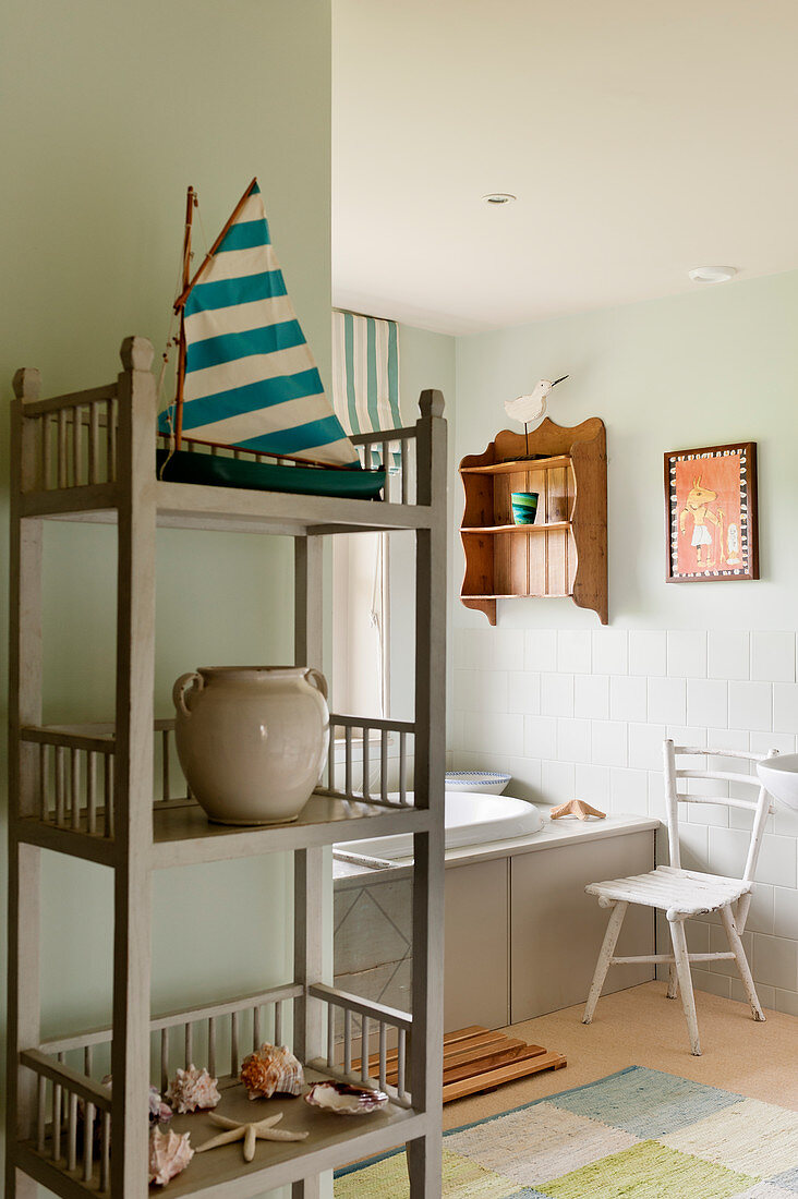 Wooden shelf in marine themed bathroom with sea shells and model boat